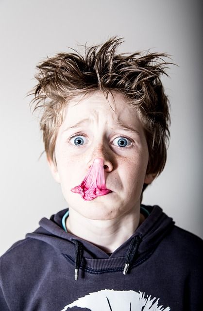 Bild zeigt einen Jungen mit einer zerplatzten Kaugummiblase im Gesicht